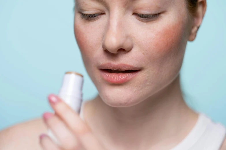 a woman holding a lip bale in front of her face, a stipple, trending on pexels, textured base ; product photos, manuka, soft shade, freezing