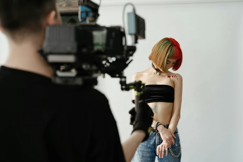 a woman that is standing in front of a camera, a tattoo, trending on pexels, video art, meet the actor behind the scenes, wearing crop top, seducing the camera, tv production