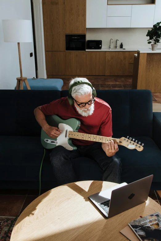 a man sitting on a couch playing a guitar, inspired by John McLaughlin, pexels contest winner, white hair and beard, using a macbook, tech demo, kakashi