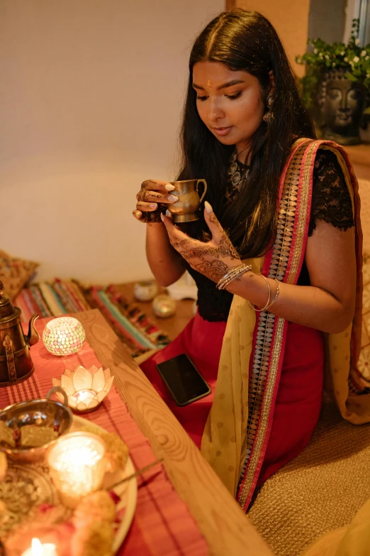 a woman sitting on a couch looking at a cell phone, hurufiyya, tea drinking and paper lanterns, anjali mudra, displayed on an altar, square