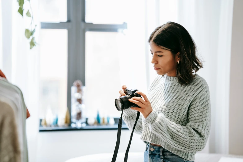 a woman standing in front of a window holding a camera, a picture, pexels contest winner, miranda cosgrove, girl in studio, eva elfie, a young asian woman