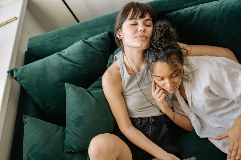 a couple of women sitting on top of a green couch, trending on pexels, cuddling, teenager girl, soft lulling tongue, diverse