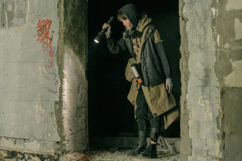 a man standing in a doorway with a flashlight in his hand, deviantart, photograph of a techwear woman, postapocalyptic, still image from tv series, woman in streetwear