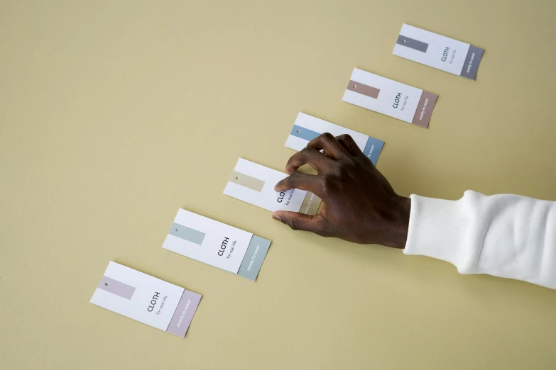 a close up of a person holding a piece of paper, by Nina Hamnett, color field, labels, neutral color, product label, multiple levels