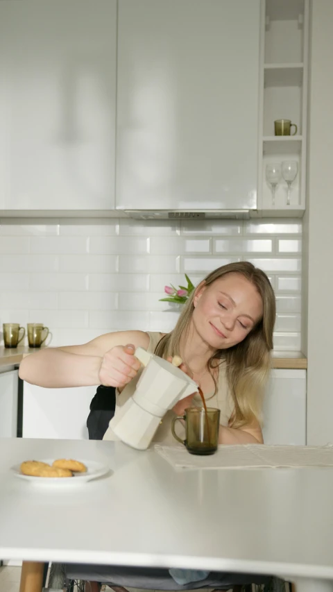 a woman pours a cup of coffee in a kitchen, inspired by Louisa Matthíasdóttir, vanilla smoothie explosion, low quality photo, dwell, thumbnail