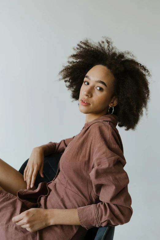 a woman sitting in a chair with her legs crossed, trending on pexels, ashteroth, hair : long brown, brown shirt, portrait featured on unsplash