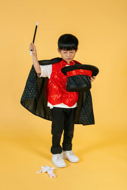 a young boy dressed as a magician holding a wand, inspired by Gong Kai, wearing nanotech honeycomb robe, black, bao pnan, red tailcoat