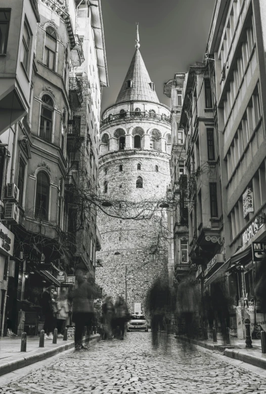 a black and white photo of people walking down a cobblestone street, inspired by Altoon Sultan, with towers, towering over your view, desaturated color, byzantine