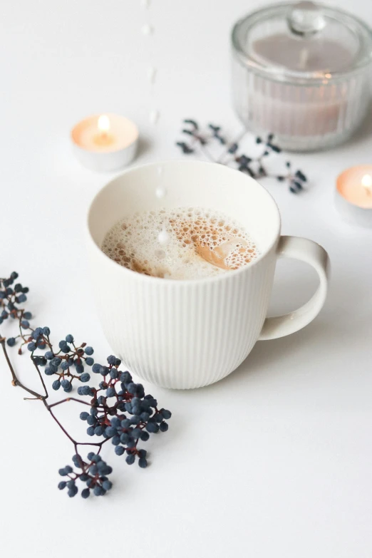 a cup of coffee sitting on top of a table, a still life, by Lucia Peka, trending on pexels, romanticism, white candles, swedish, on grey background, manuka