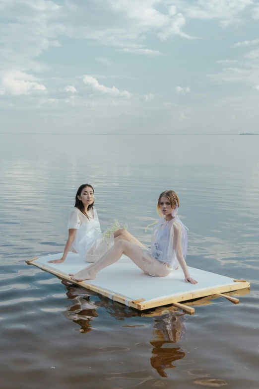 two women sitting on a floating platform in the water, unsplash, conceptual art, white, picnic, ruan jia and brom, studio shot