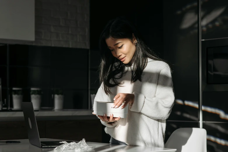 a woman sitting at a table with a cup of coffee, white box, wearing a white sweater, japanese collection product, glowing inside