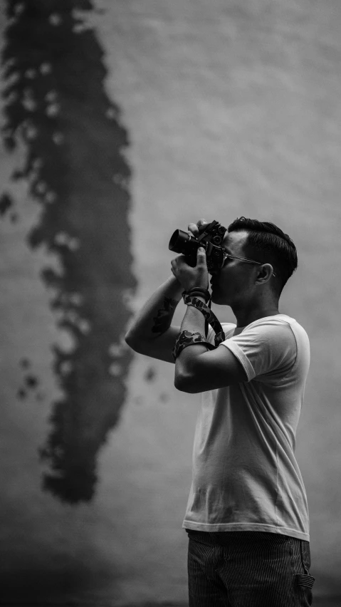 a man taking a picture with a camera, a black and white photo, pexels contest winner, minimalism, asian male, profile pose, today\'s featured photograph 4k, half body photo