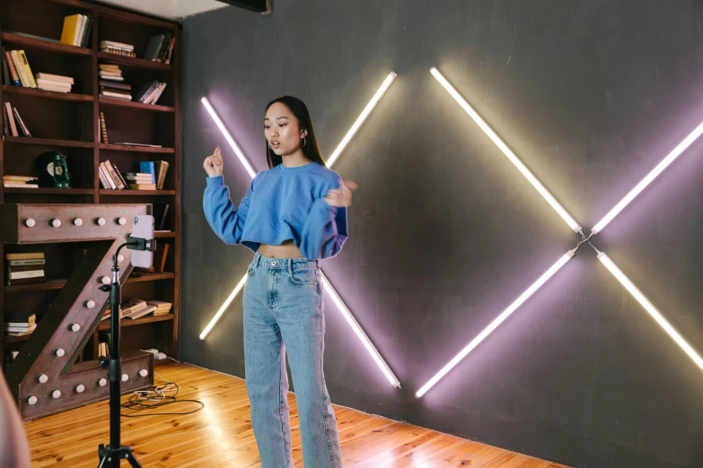 a woman standing in front of a camera in a room, a hologram, inspired by Li Di, trending on pexels, interactive art, led light strips, product introduction photo, joy ang, pointing