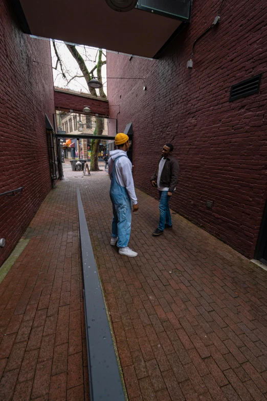 a man riding a skateboard down a brick walkway, an album cover, by Jan Tengnagel, trending on unsplash, two men, standing in an alleyway, portland oregon, calmly conversing 8k