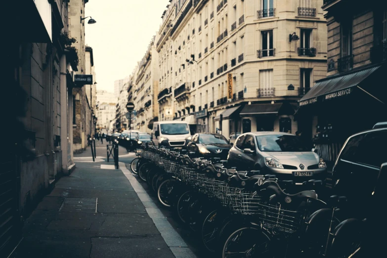 a street filled with lots of parked bikes, a photo, pexels contest winner, paris school, 🚿🗝📝, with instagram filters, cars parked underneath, fine art print