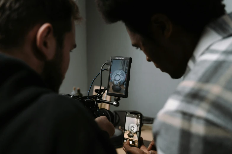 a man standing next to another man holding a camera, pexels contest winner, video art, close up to the screen, looking down on the camera, production ig, cinematic counter light