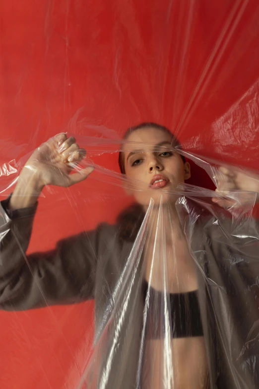 a woman holding a plastic bag over her head, an album cover, inspired by Anna Füssli, pexels contest winner, plasticien, ignant, glossy plastic, still from a movie, red mesh in the facede