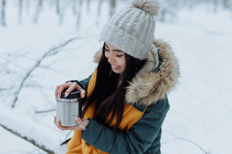 a woman standing in the snow holding a cup, pexels contest winner, hurufiyya, having a picnic, avatar image, asian female, holding a tin can