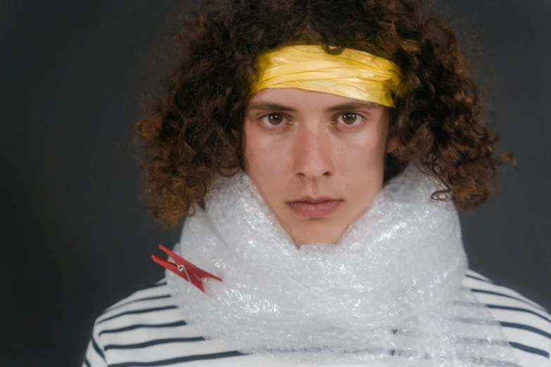 a man with curly hair wearing a scarf, inspired by Anna Füssli, trending on pexels, plasticien, covered in bandages, costume, press shot, made of plastic