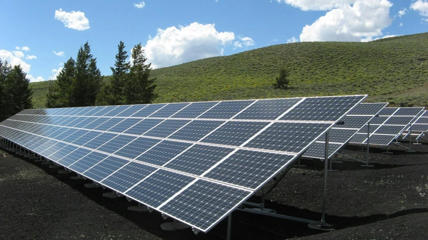 a large array of solar panels in a field, by Carey Morris, pixabay, rolling green hills, shadowy, low angle photo, 15081959 21121991 01012000 4k