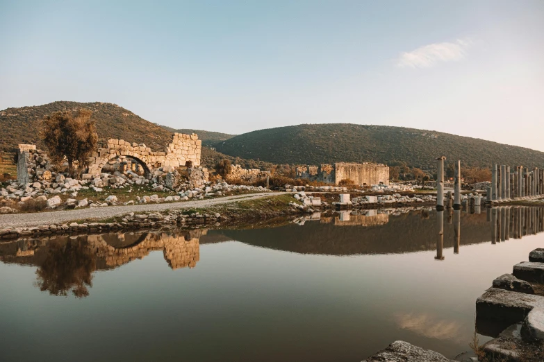 a large body of water surrounded by rocks, pexels contest winner, les nabis, aqueduct and arches, in front of a ruined city, turkey, reflections on the river