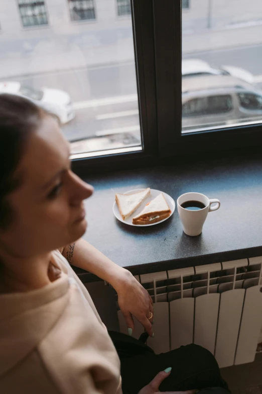 a woman sitting in front of a window with a cup of coffee, inspired by Elsa Bleda, pexels contest winner, renaissance, snacks, human staring blankly ahead, breakfast, gif