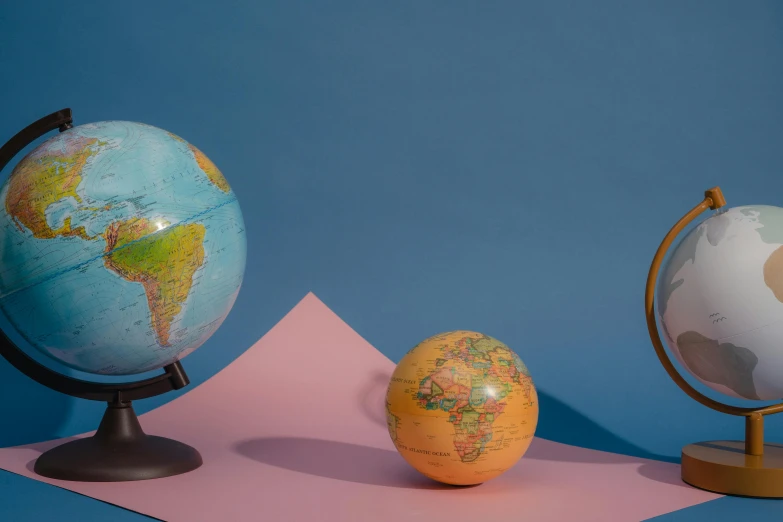 a couple of globes sitting on top of a pink piece of paper, replica model, multicoloured, explorer, various posed