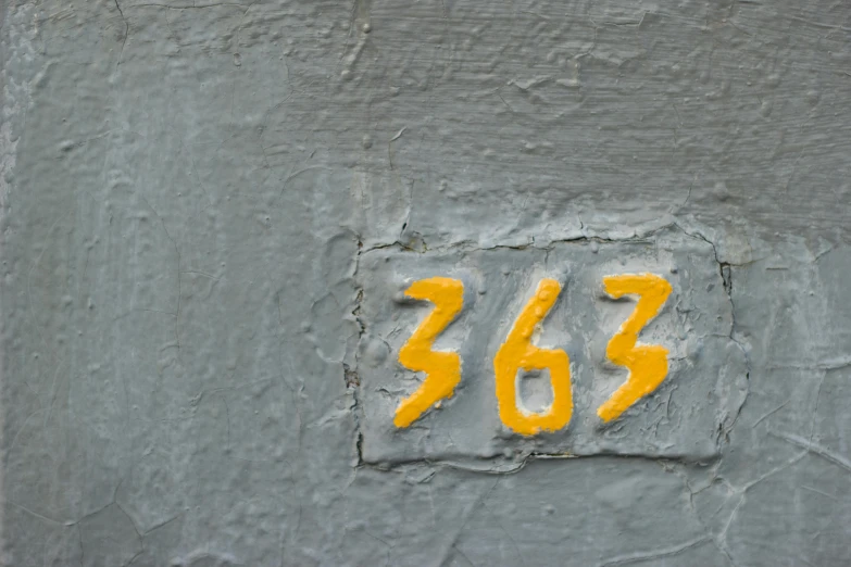 a close up of a number on the side of a building, inspired by Derek Jarman, pexels contest winner, triple six, metro 2 0 3 3, yellow, gray concrete