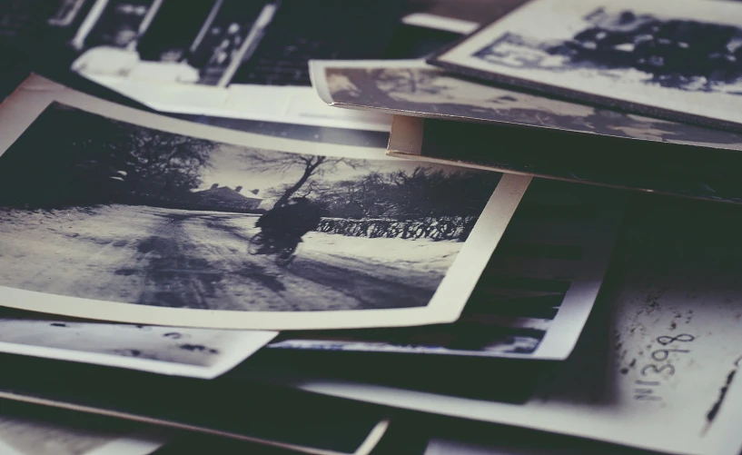 a pile of old photos sitting on top of a table, a black and white photo, by Lucia Peka, unsplash, retro effect, clean post process, multiple stories, dark and intricate photograph