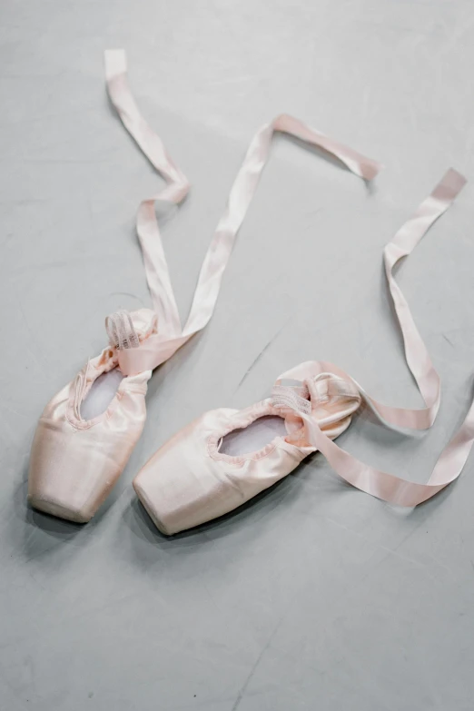 a pair of ballet shoes sitting on top of a floor, satin ribbons, light pink tonalities, press photos, ap news