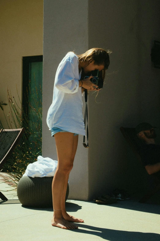 a woman taking a picture with a camera, a picture, inspired by Elsa Bleda, unsplash, process art, skimpy shorts, in the yard, face down, cara delevingne standing