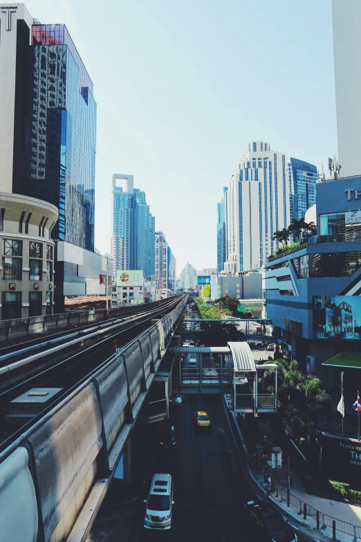 a train traveling through a city next to tall buildings, unsplash, thailand, square, iphone picture, 4k]