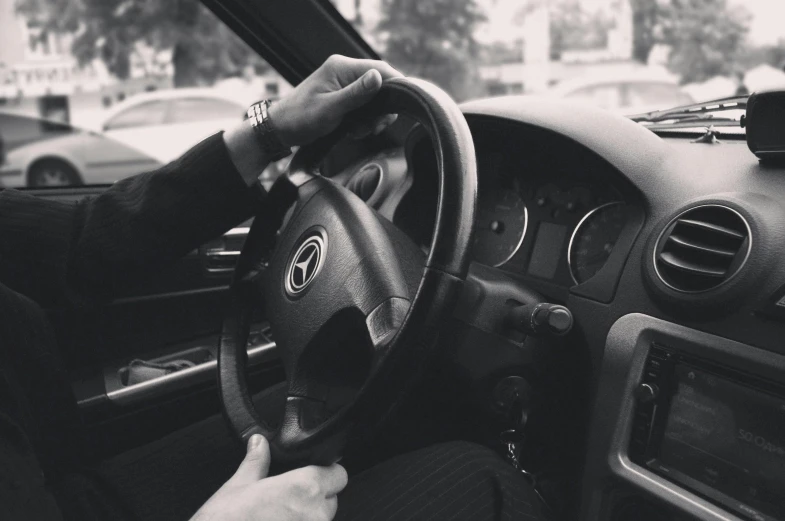 a black and white photo of a person driving a car, 🚿🗝📝, hand controlling, promo image, instagram post