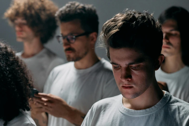 a group of young men standing next to each other, by Adam Marczyński, pexels contest winner, hyperrealism, movie still of a tired, hair, yung lean, looking at his phone