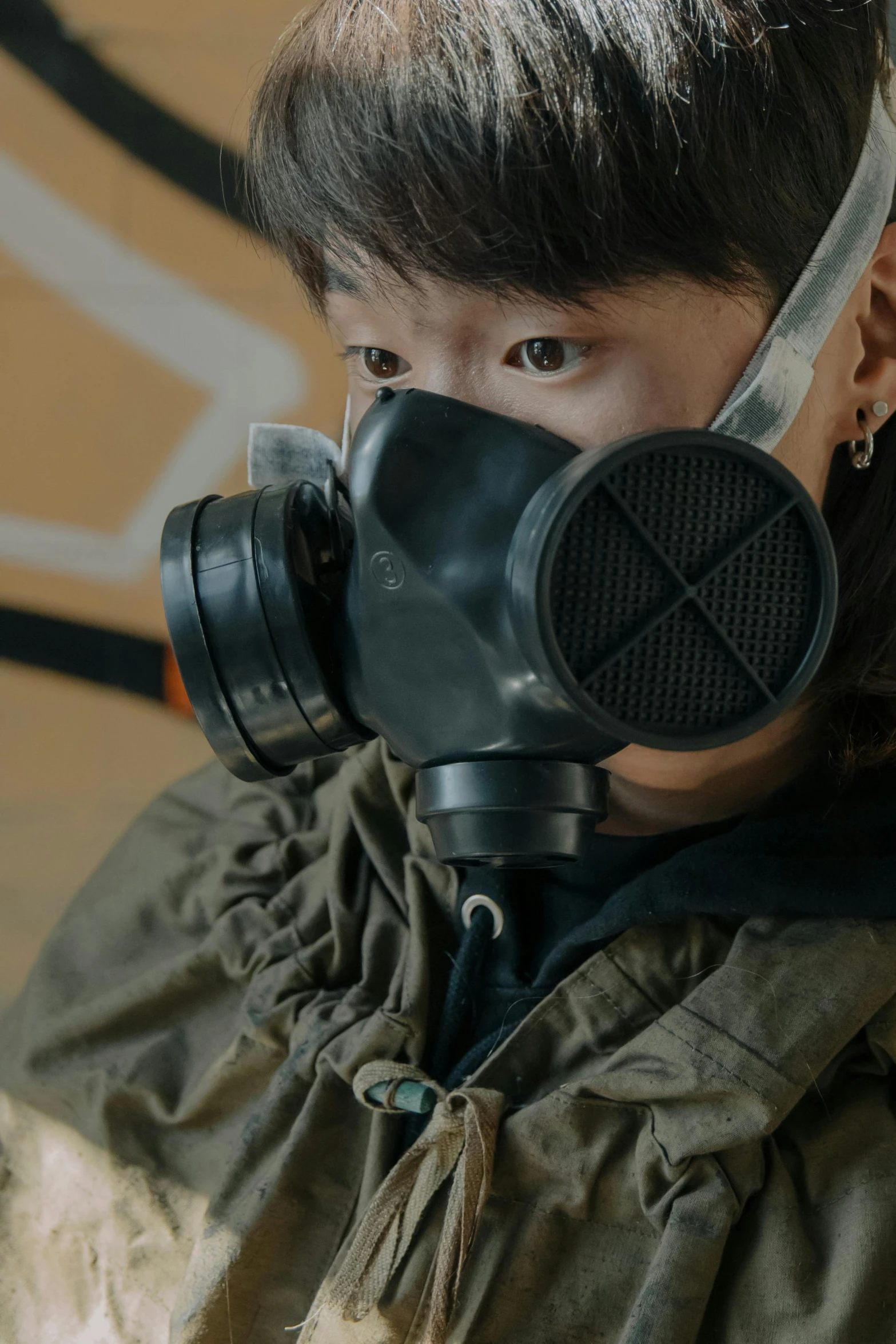 a person wearing a gas mask in front of a graffiti wall, pexels contest winner, cai xukun, live-action adaptation, kids, black