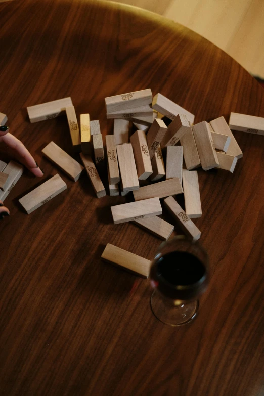 a person playing with wooden blocks on a table, by Joel Shapiro, unsplash, wine, gold and silver shapes, photographed for reuters, lost runes