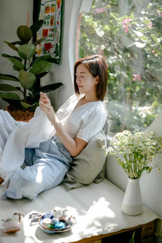 a woman sitting on top of a couch next to a window, inspired by jeonseok lee, unsplash, wearing casual clothing, in garden, lined in cotton, soft features