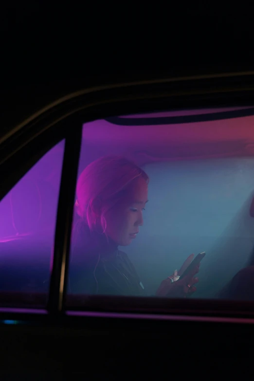 a woman sitting in a car looking at her cell phone, inspired by Nan Goldin, conceptual art, ((purple)), still from riverdale, lee madgwick & liam wong, fluorescent