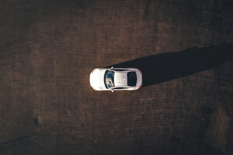 a white car sitting on top of a dirt road, pexels contest winner, minimalism, game top down view, square, long shadow, gradient brown to white