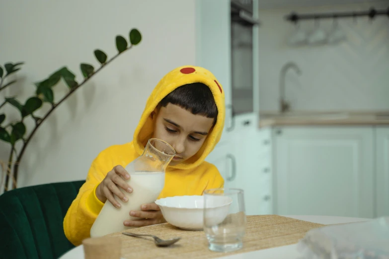 a young boy in a yellow hoodie pours milk into a bowl, pexels contest winner, avatar image, mukbang, enes dirig, a mysterious