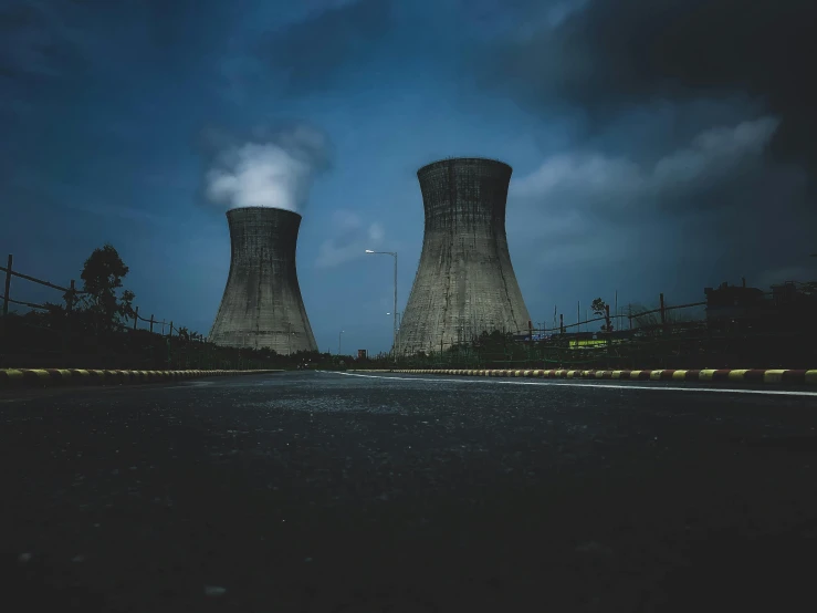 two cooling towers with smoke coming out of them, a colorized photo, inspired by Elsa Bleda, pexels contest winner, nuclear art, night photo, concrete pillars, ground level shot, grey