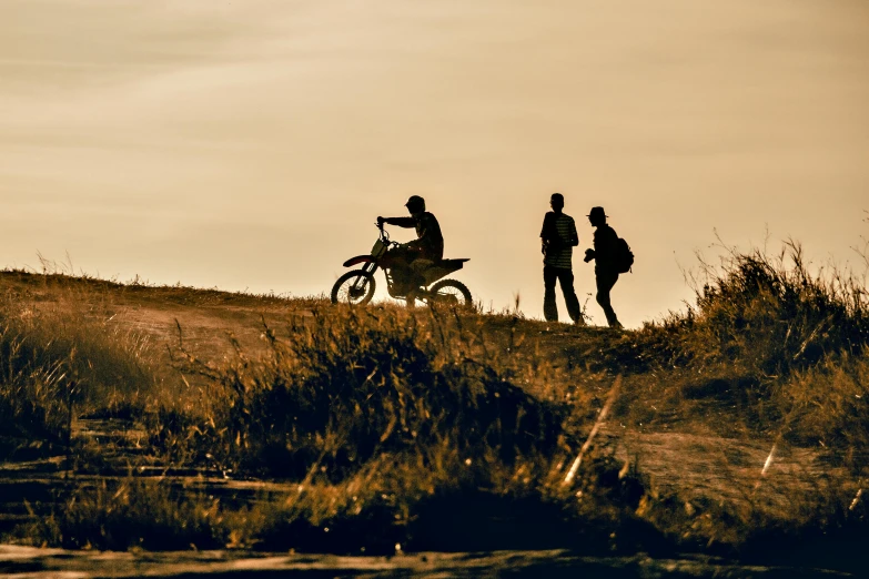 a couple of people standing next to a dirt bike, by Daniel Seghers, pexels contest winner, figuration libre, late summer evening, top of the hill, profile image, zoomed in