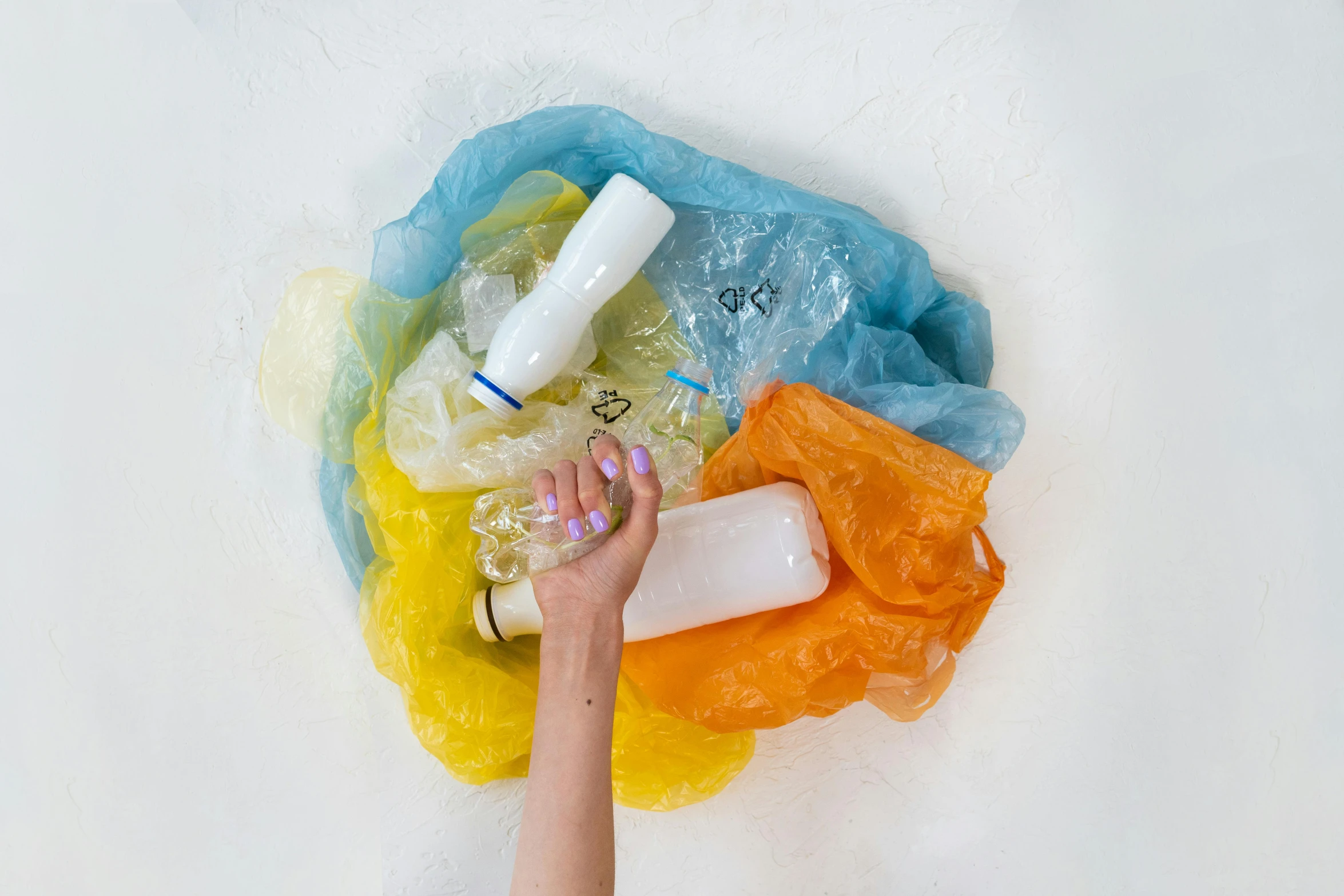 a person laying on a bed covered in plastic, inspired by Helen Frankenthaler, pexels contest winner, plasticien, colorful bottles and plants, white and yellow scheme, rainbow tubing, flat lay