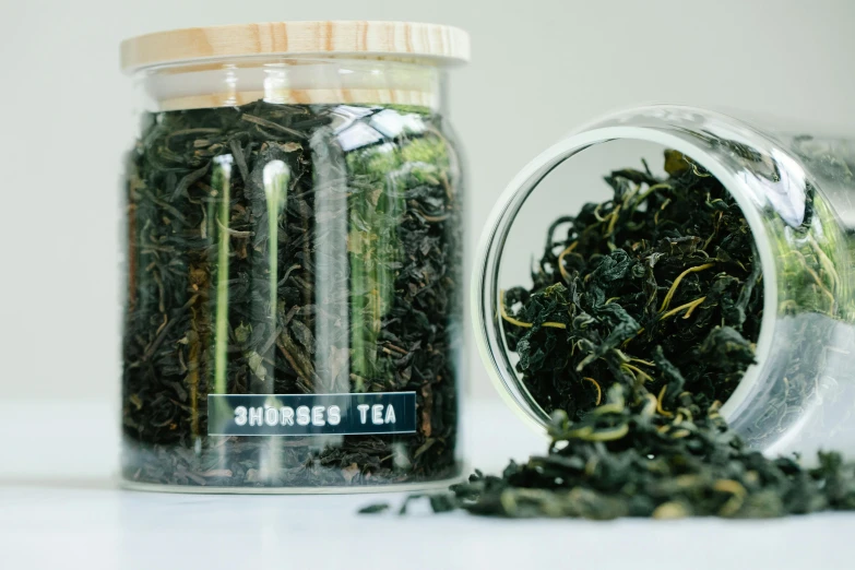 a jar filled with green tea sitting on top of a table, by Emma Andijewska, pexels, smoked layered, product label, jar on a shelf, crushed