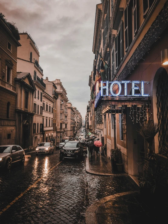 a street lined with parked cars next to tall buildings, an album cover, unsplash contest winner, neoclassicism, all roads lead to rome, rainy evening, hotel room, dilapidated neon signs