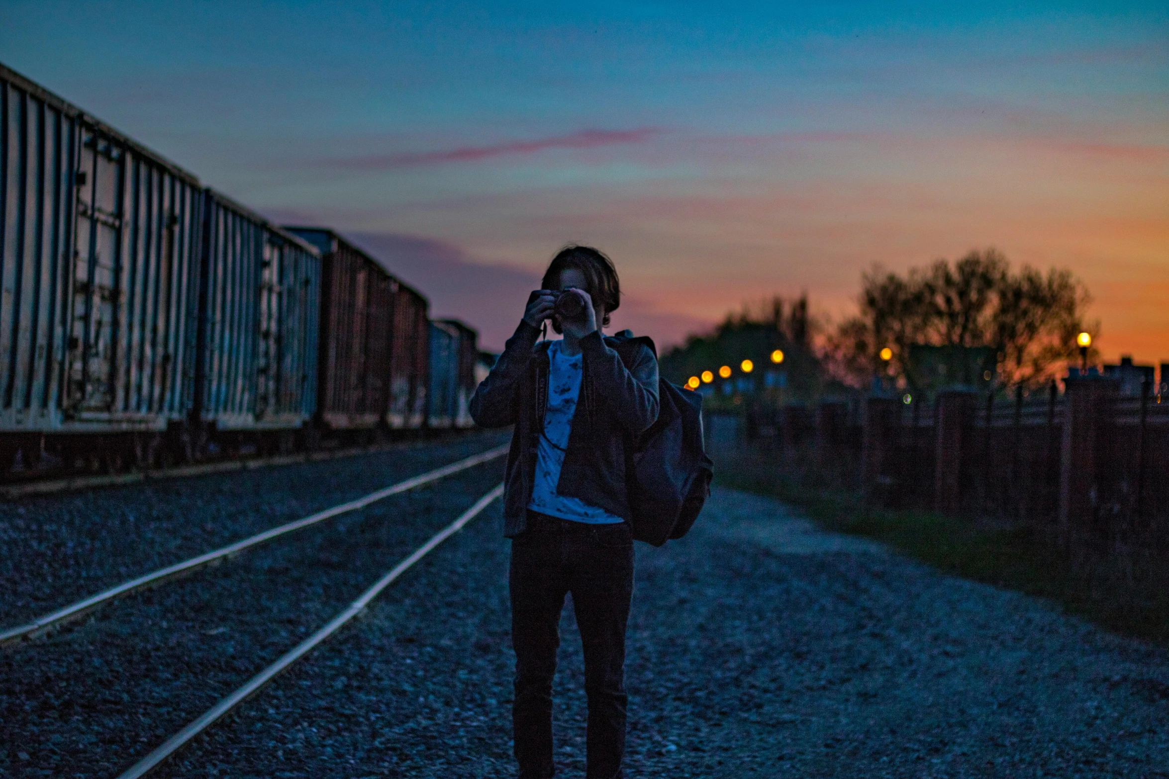 a woman standing on a train track talking on a cell phone, a picture, pexels contest winner, a man wearing a backpack, predawn, alternate album cover, profile pic