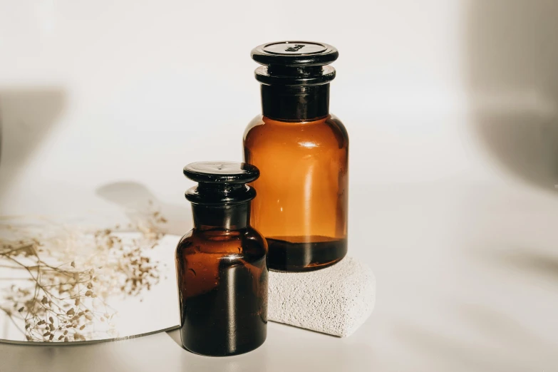 a couple of bottles sitting on top of a counter, by Emma Andijewska, trending on pexels, apothecary, background image, brown resin, powder