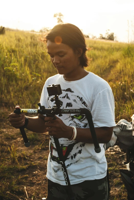 a man standing in a field holding a camera, action sports, thawan duchanee, uav, tie-dye