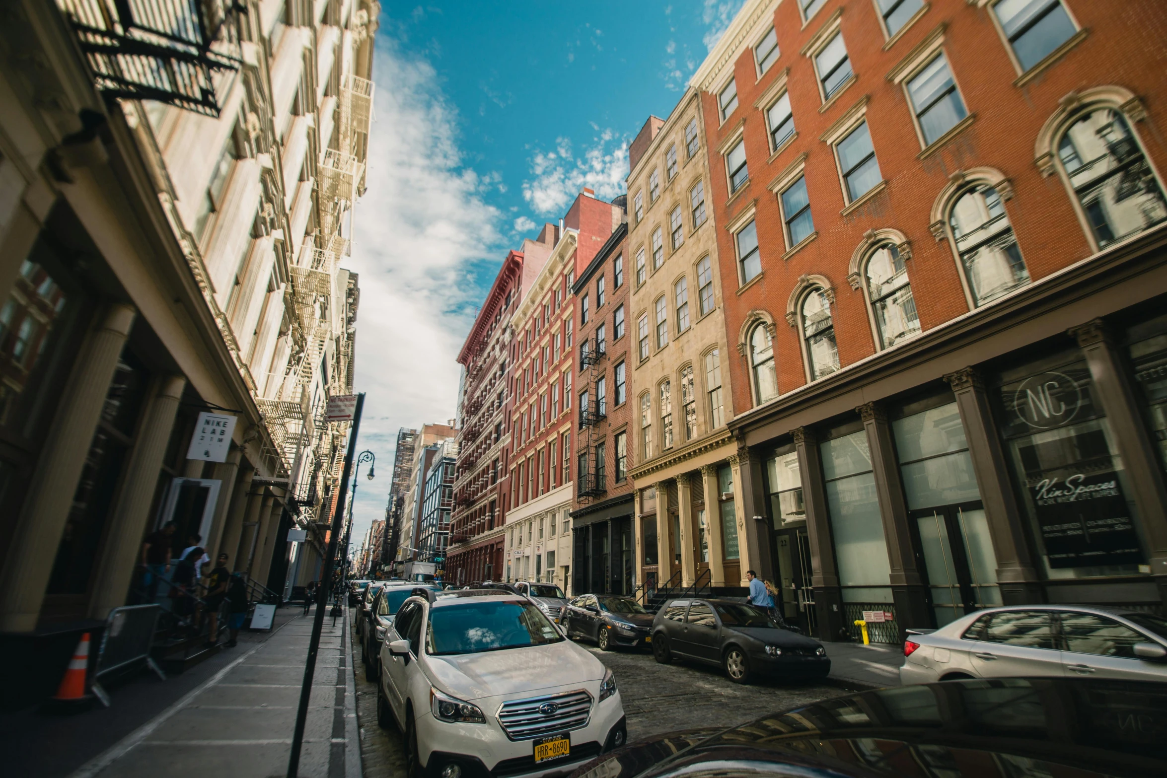 a city street filled with lots of tall buildings, a photo, new york alleyway, profile image, fan favorite, cars parked underneath