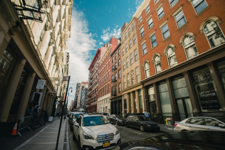 a city street filled with lots of tall buildings, a photo, new york alleyway, profile image, fan favorite, cars parked underneath
